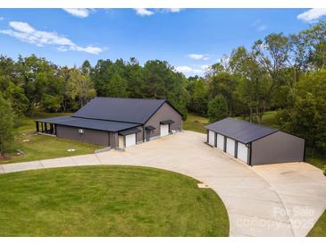 Stunning exterior view of a modern barn home with a spacious driveway and detached three-car garage at 5070 Woodleaf Rd, Salisbury, NC 28147