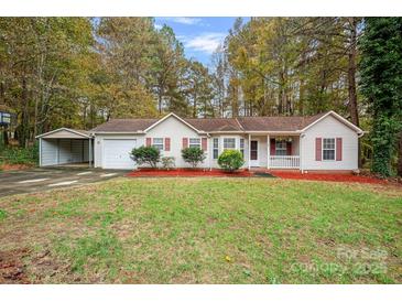 Charming ranch-style home with a one-car garage, carport, red mulch beds, and a well-manicured lawn at 113 Julius Ln, Mooresville, NC 28117