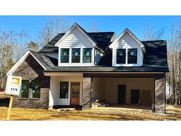 Two-story home with brick and white siding, a large garage, and a charming front yard at 1176 Greenheather Dr, Salisbury, NC 28147