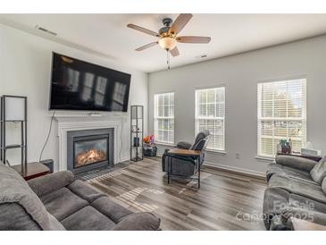 Bright living room with a ceiling fan, fireplace, and modern flooring for a comfortable atmosphere at 2512 Holly Oak Ln, Gastonia, NC 28056