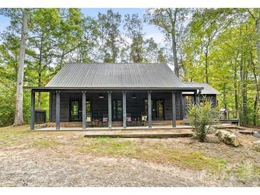 Dark-colored cabin with a large front porch and metal roof, nestled in a wooded setting at 1386 Old Pinckney Rd, York, SC 29745