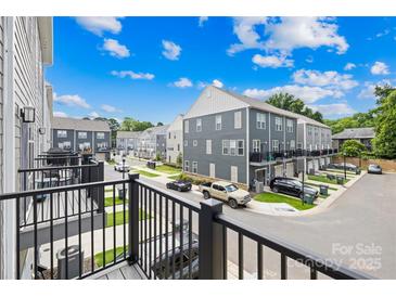 View of modern townhomes with gray siding, manicured lawns, and ample parking on a sunny day at 4018 Capital Ridge Ct, Charlotte, NC 28205