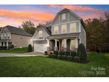 Two-story house with gray siding, stone accents, and a landscaped lawn at 2624 Woodlands Creek Dr, Monroe, NC 28110