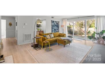 Bright living room with hardwood floors, large windows, and stylish mustard yellow couch at 7062 Quail Hill Rd, Charlotte, NC 28210