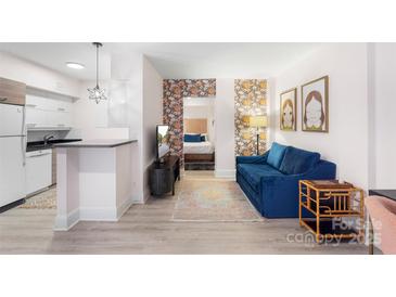 Bright living room with blue sofa, and view into bedroom and kitchen at 400 Queens Rd # E5, Charlotte, NC 28207