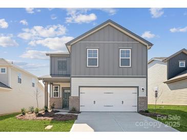 Charming two-story home with gray siding, brick accents, and an attached two-car garage at 2565 Blue Sky Meadows Dr, Monroe, NC 28110