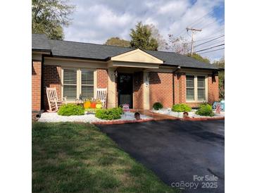 Brick ranch home with rocking chairs, landscaping, and a paved driveway at 1204D Northgate Dr, Shelby, NC 28150