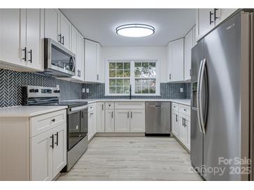 Modern kitchen features white cabinets, stainless steel appliances, and herringbone backsplash at 4601 Coronado Dr # C, Charlotte, NC 28212