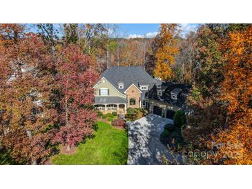 Charming two-story home featuring a stone facade, manicured lawn, and mature trees at 20361 Enclave Oaks Ct, Cornelius, NC 28031