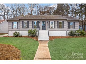 Charming home featuring a well-maintained front yard, a welcoming walkway, and classic shutters enhancing its curb appeal at 9027 Twin Trail Dr, Huntersville, NC 28078