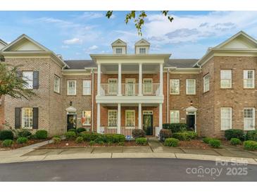 Charming brick townhouse with white columns, two-story porch, and manicured landscaping at 8336 Indigo Row, Charlotte, NC 28277