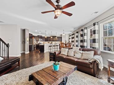 Open living room featuring hardwood floors, a ceiling fan, and a leather sofa that flows to the kitchen at 2741 Smethwick Ln, Gastonia, NC 28056