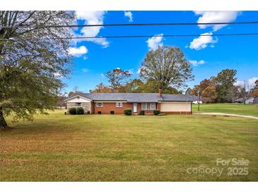 Charming brick single-story home featuring a well-maintained lawn and mature trees under a beautiful blue sky at 4501 Taylorsville Hwy, Statesville, NC 28625