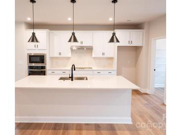 Bright kitchen with quartz counters, stainless appliances, and black pendant lighting at 7928 Cedarsmith Ct, Charlotte, NC 28217