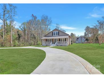 Inviting home features a circular driveway and a charming front porch, set against a backdrop of lush greenery at 12300 Caldwell Rd, Charlotte, NC 28213