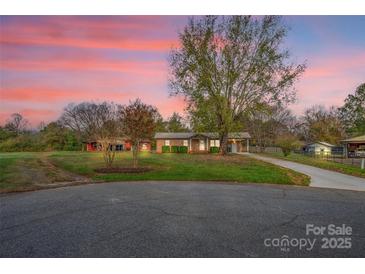 Charming single-story brick home with a long driveway, spacious yard, and beautiful mature trees at dusk at 130 Island Park Ln, Statesville, NC 28625