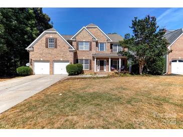 Charming brick home with two-car garage, manicured lawn, and inviting front porch at 3848 Burnage Hall Rd, Harrisburg, NC 28075