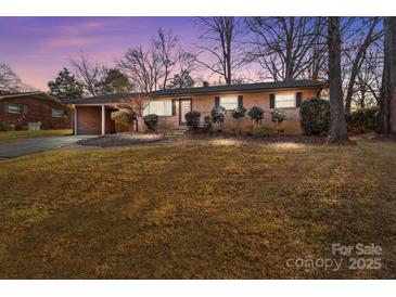 Charming brick home featuring a well-maintained lawn and convenient carport at 555 Westwood Dr, Kannapolis, NC 28081