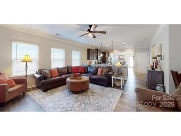 Bright living room featuring a ceiling fan, wood floors, and an open floor plan with a view to the kitchen at 280 Kerri Dawn Ln, Locust, NC 28097