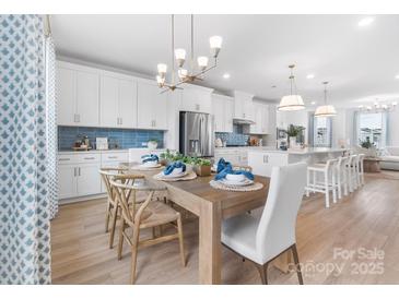 Bright open-concept dining room featuring modern lighting, light wood floors, and seating for six at 2146 Barrowcliffe Nw Dr, Concord, NC 28027