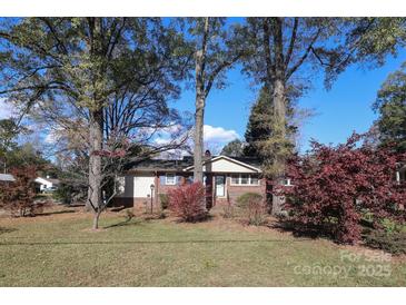 Brick ranch house with a landscaped lawn and mature trees at 2701 Palm Ave, Charlotte, NC 28205