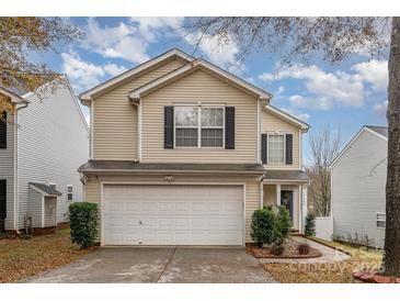 Two-story house with beige siding, a white garage door, and landscaping at 7546 Lady Liberty Ln, Charlotte, NC 28217