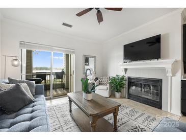 Cozy living room with a fireplace, ceiling fan and a sliding glass door to a private balcony at 907 Southwest Dr, Davidson, NC 28036