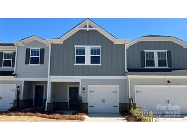 Charming townhome with a two-car garage and stylish gray siding, providing a welcoming curb appeal at 1618 Village Grove Ln, Monroe, NC 28110