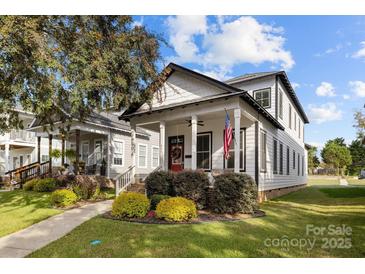 Charming two-story home featuring a covered porch, American flag, and well-manicured landscaping at 511 E Main St, Rock Hill, SC 29730
