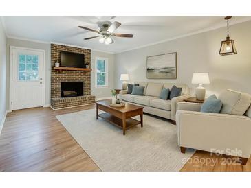 Inviting living room with brick fireplace, ceiling fan, and neutral-toned furniture at 13446 Idlefield Ln, Matthews, NC 28105