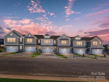 Charming new townhomes featuring varied siding and garage doors under a beautiful evening sky at 153 Halite Ln, Waxhaw, NC 28173