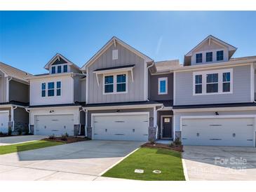 Charming townhomes featuring a two-car garage, neutral siding, and manicured lawns on a sunny day at 157 Halite Ln, Waxhaw, NC 28173