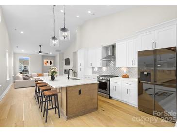 Open concept kitchen with island, stainless steel appliances, and hardwood floors at 2205 Catalina Ave, Charlotte, NC 28206