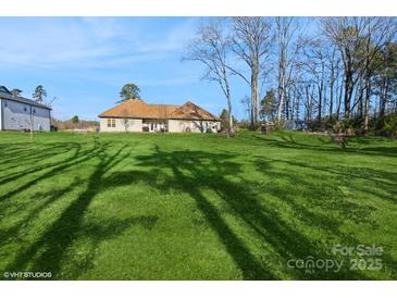 Spacious backyard with a large grassy area and mature trees at 1808 Wilton Gate Dr, Charlotte, NC 28262