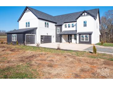 Two-story farmhouse with black and white exterior, attached garage, and landscaping at 3907 E Lawyers Rd, Monroe, NC 28110