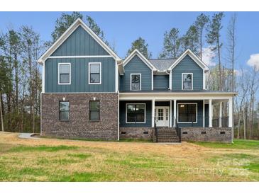 Two-story home featuring a blend of brick and blue siding, complemented by a welcoming front porch at 357 Triple Ponds Ct, Clover, SC 29710