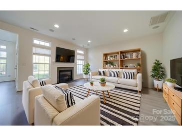 Bright living room with a fireplace, large windows, and stylish striped rug, creating a cozy atmosphere at 11628 Eastwind Dr, Charlotte, NC 28273