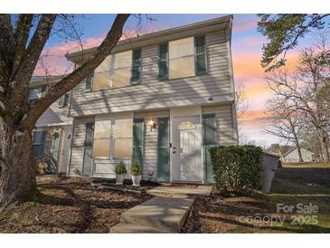 Charming townhome featuring white siding, teal shutters, and a cozy front entrance during a beautiful sunset at 5300 Fair Wind Ln, Charlotte, NC 28212