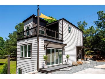 A contemporary two-story home featuring a balcony, modern siding and lush landscaping at 6534 Providence Rd, Charlotte, NC 28226