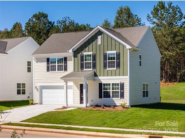 Two-story house with neutral siding, green accents, and a two-car garage at 1604 Cannonball Ln, Bessemer City, NC 28016