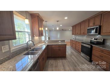 Updated kitchen featuring granite countertops, stainless steel appliances and wood cabinets at 433 Pamela St, Gastonia, NC 28054