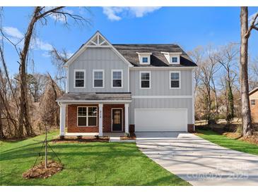 New construction home featuring gray siding, brick accents, an attached garage, and a well-manicured lawn at 3110 Westerwood Dr, Charlotte, NC 28214