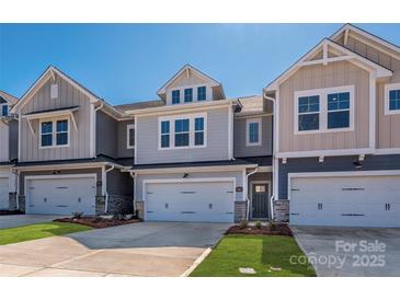 View of craftsman-style townhomes showcasing neutral exteriors, garage doors, and well-manicured lawns under a clear blue sky at 161 Halite Ln, Waxhaw, NC 28173