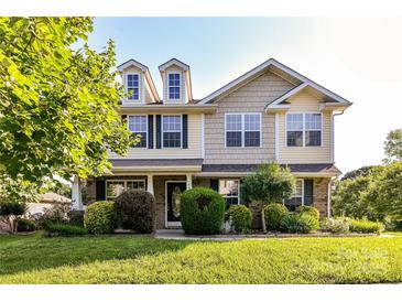 Charming two-story home featuring dormer windows, a manicured lawn, and mature landscaping at 7534 April Mist Trl, Huntersville, NC 28078