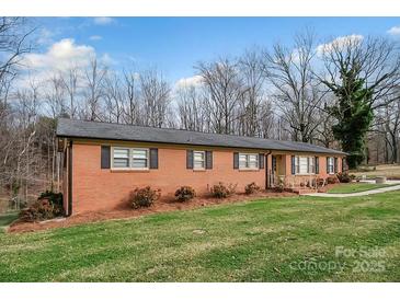 Charming red brick home with a well-maintained lawn and mature trees creating a serene curb appeal at 216 Delview Dr, Cherryville, NC 28021