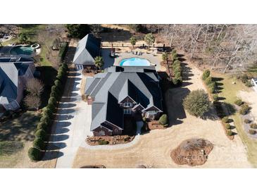 An aerial view of a luxurious home featuring a pool, landscaped backyard, and a private setting surrounded by trees at 1038 Rolling Park Ln, Fort Mill, SC 29715