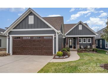 Charming gray home featuring a brown garage door, manicured lawn, and a welcoming covered front porch at 112 Sisters Cove Ct, Mooresville, NC 28117