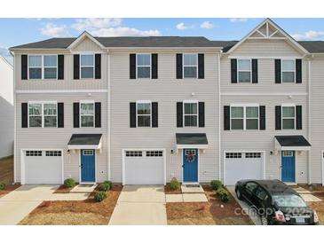 A row of townhomes featuring blue doors, white garages and siding, and neatly trimmed landscaping at 2409 Fathom Way, Charlotte, NC 28269
