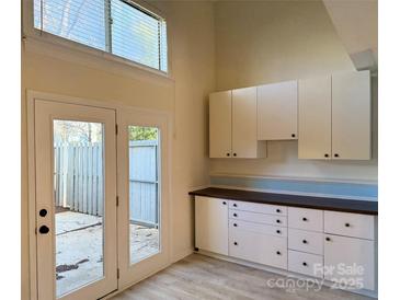 Bright kitchen with white cabinets, patio access, and wood-look floors at 6130 Heathstone Ln, Charlotte, NC 28210