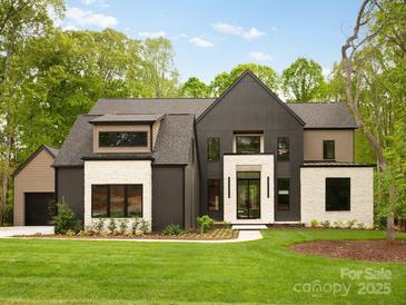 Stunning modern home featuring a black and stone exterior with a well-manicured lawn at 116 Hunt Camp Trl # 11, Davidson, NC 28036